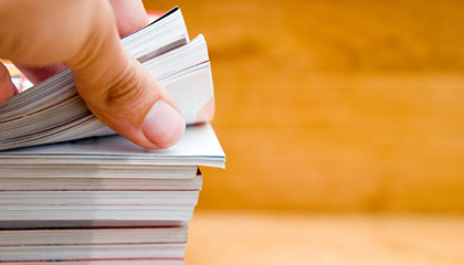 Hand browsing through stack of journals and  magazines