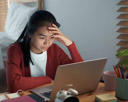 Asian girls are sitting bore online with a tutor on a laptop while sitting in the bedroom at home night. concept online learning at home